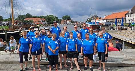 Eine Gruppe von Personen in blauen Trikots steht am Hafen.