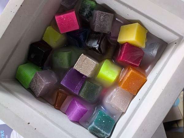 Betonwürfel gefüllt mit bunten Wachs-Vierecken