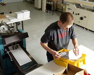 Ein Mitarbeiter sortiert gedruckte Materialien in einer Druckerei.
