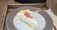 Ein Stück Sahnetorte mit Dekoration auf einem grauen Teller.