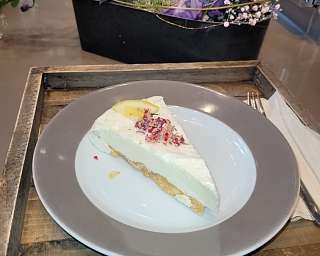 Ein Stück Torte mit Sahne und Dekoration auf einem grauen Teller.