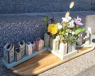 Keramisches Blumenarrangement mit bunten Häusern und Blumen.